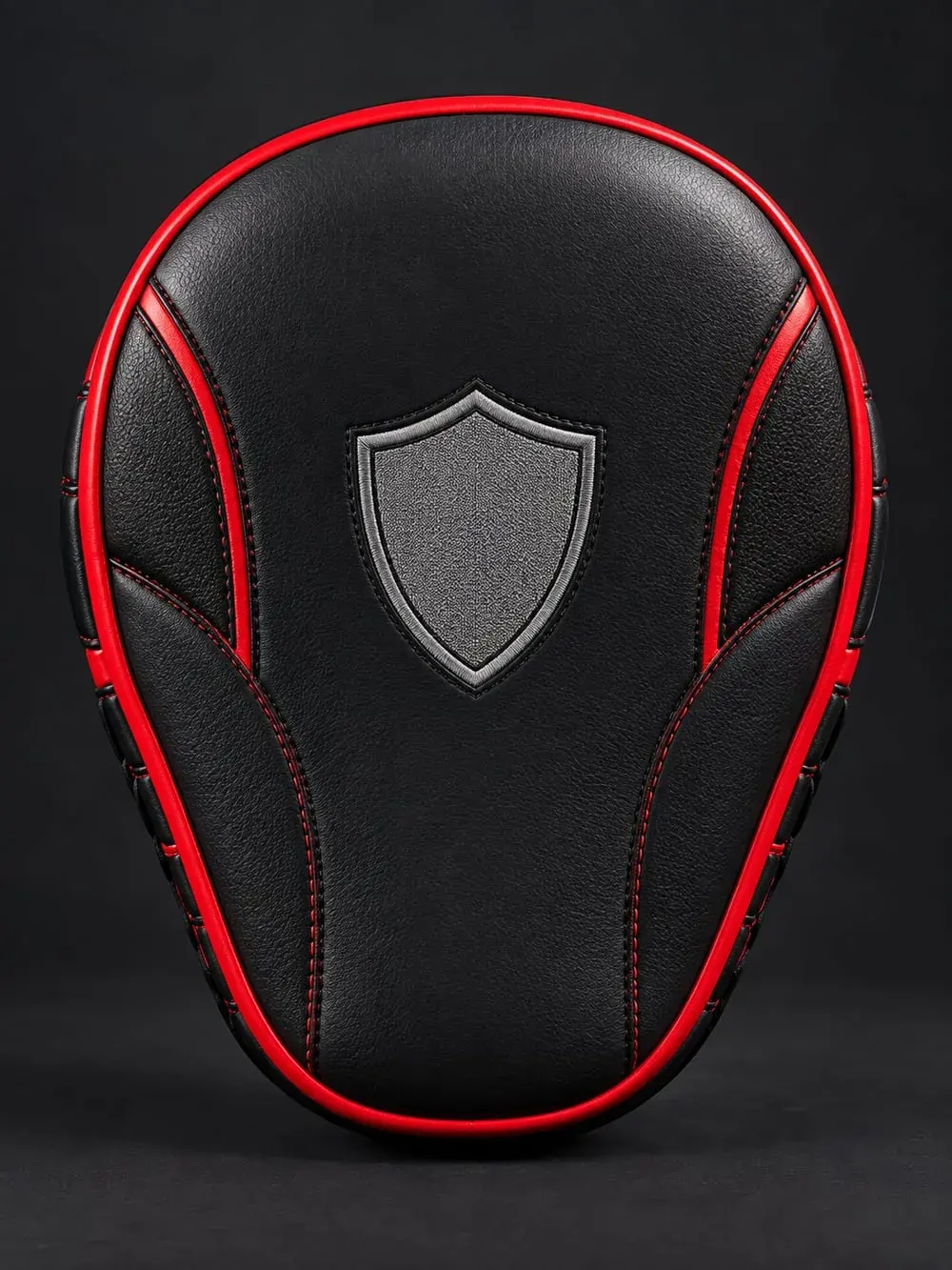 The finished black leather focus mitt with red piping, the grey shield emblem on the striking face as in the drawing.