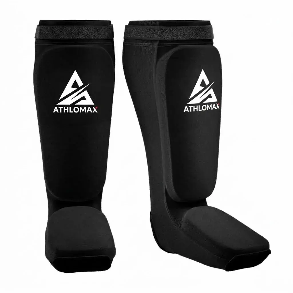 A pair of black stretch-fabric Athlomax shin and instep guards with padded shins and insteps and a white Athlomax logo on each shin.