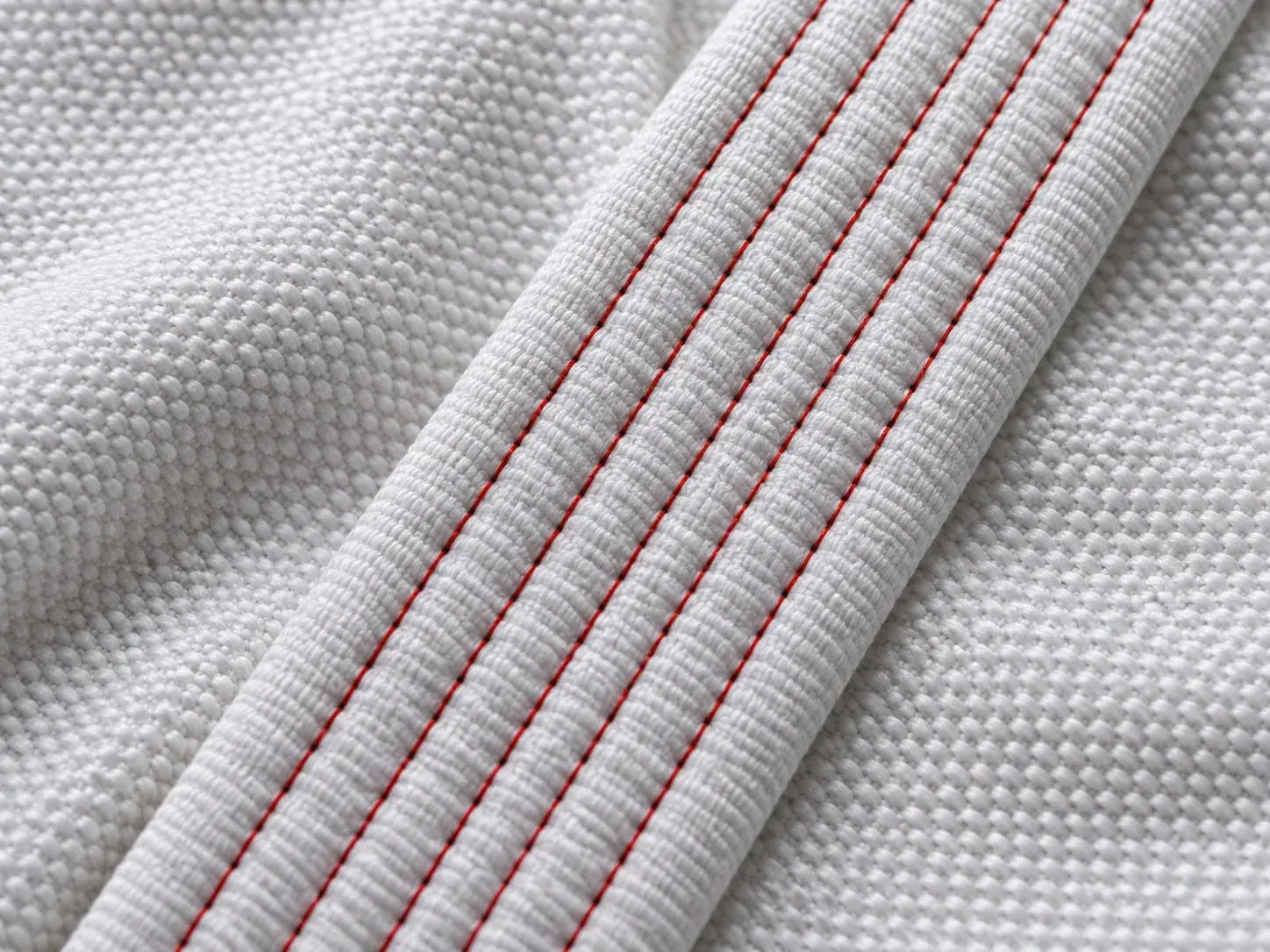 White pearl weave cotton beside a thick gi collar stitched in rows of red thread.
