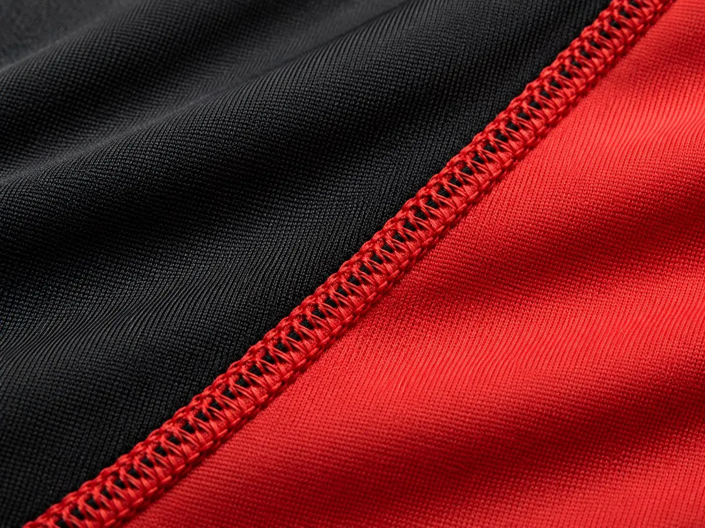 Black and red stretch performance fabric joined by a red overlocked seam.