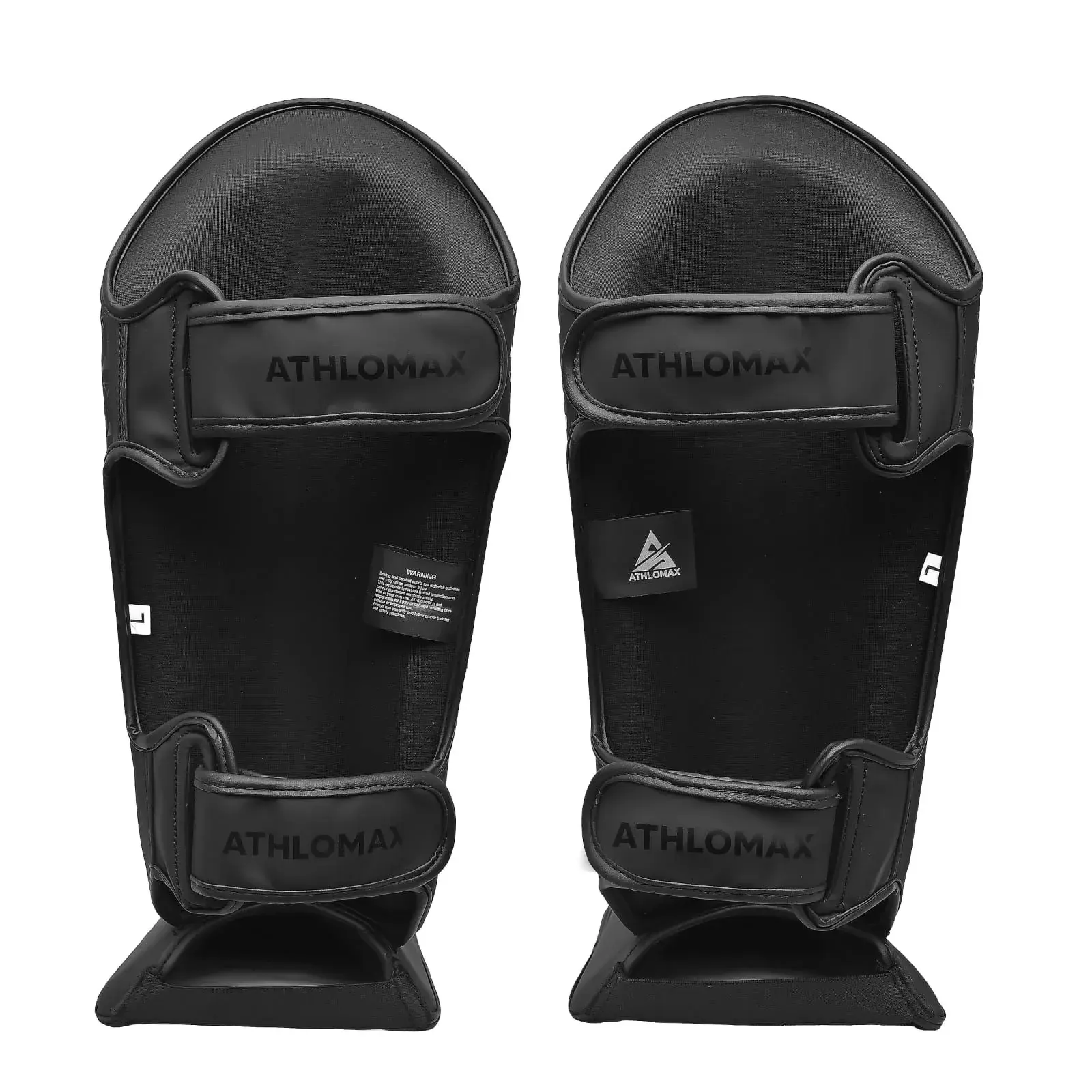 The inside of the same shin guards: the Athlomax wordmark on both hook-and-loop straps, a brand label and a warning label.